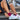 Person tying white athletic shoe laces on outdoor concrete steps, wearing red socks. The scene conveys readiness and focus.