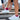 Person tying white athletic shoe laces on outdoor concrete steps, wearing red socks. The scene conveys readiness and focus.